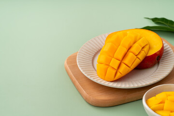 Fresh ripe mango with cubes on green table background.