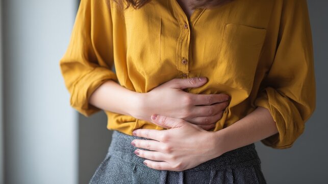 A worried person pressing gently on their abdomen trying to relieve pain caused by muscle strain or gastrointestinal issues