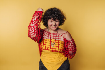Young woman celebrates joyfully in vibrant yellow and red against a bold backdrop during a cheerful moment