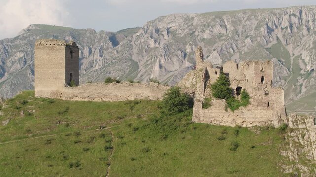 Cinematic drone shot slowly ascending to reveal the medieval Trascău Fortress ruins in Colțești, Romania. An epic historical landmark in the mountains of Transylvania.