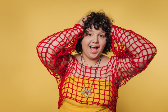 Woman expresses joy and excitement while wearing colorful outfit against a vibrant yellow background