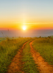 Landscape view of countryside dirt road path crosses the hills with sunset sky background.