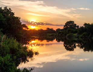 The serene, calm waters of the Kwanza River, reflecting a brilliant sunset sky, framed by lush riverine vegetation.