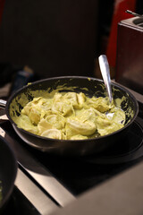 sartén con tortellini relleno y salsa en una sartén en la vitrocerámica de la cocina