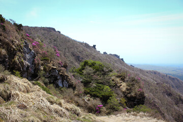 Mountain ridge on Hallasan volcano, Jeju Island, South Korea, with rocky slopes, spring azaleas and panoramic view over the landscape below.