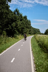 Two adults enjoy leisurely bike ride along picturesque country path surrounded by lush greenery
