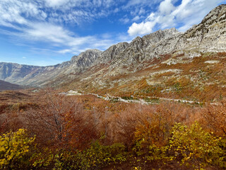Scenic autumn view of the mountains and valley in Malësi e Madhe, northern Albania, with vibrant foliage and rugged peaks.