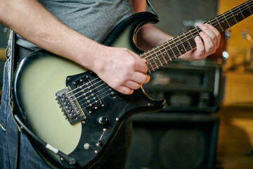 Close up of musician hands playing an electric bass guitar, focusing on precise finger placement...