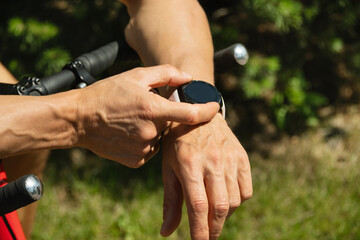 Athlete cyclist checking distance, pulse or fitness progress in apps after riding. Close up man...