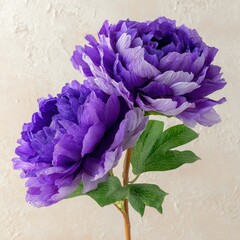 Two ombre purple artificial peonies on a single stem with green leaves against a textured background