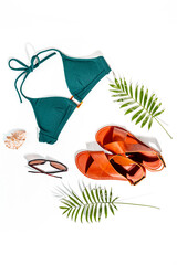Stylish bikini swimsuit with sandals and tropical leaves, top view. Vacation beach accessories