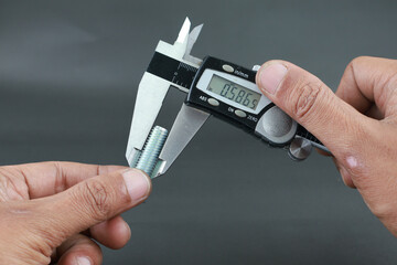 Hand measure diameter hex bolt using digital vernier caliper on black background. Universal tool...