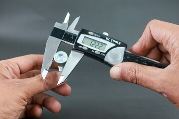 Hand measure diameter hex bolt using digital vernier caliper on black background. Universal tool...