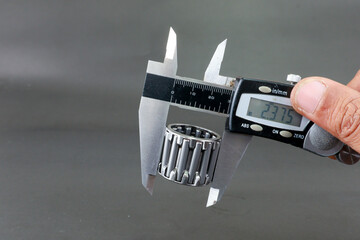 Hand measure diameter roller bearing using digital vernier caliper on black background. Universal...