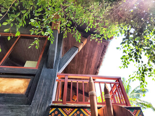 Traditional wooden structure with balcony surrounded by greenery in a tropical setting captures the...