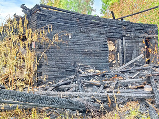 Fire-damaged building with charred remains in a rural area after a recent blaze