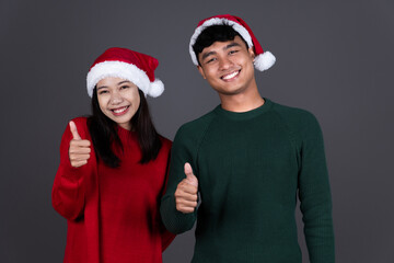 Portrait of Positive Young Asian Man and Woman Thumbs Up Wearing Santa Hat, Christmas Holiday Concept