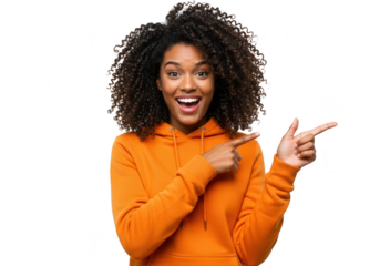 An excited young african woman in an orange hoodie points forward with a smile, isolated on white isolated on transparent background