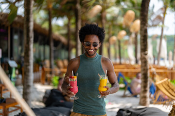 Smiling man in sunglasses holding colorful tropical smoothies on a sunny beach with palm trees, enjoying a relaxing summer vacation atmosphere