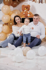 Family celebrates first birthday with decorations and balloons in cozy indoor setting