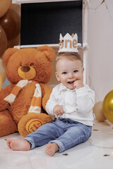 Toddler celebrates first birthday with cheerful decorations and a plush bear