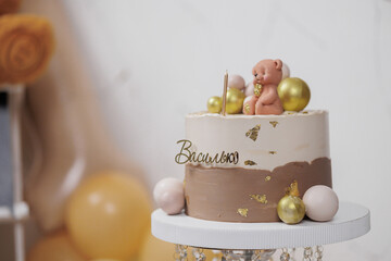 Celebratory cake featuring a teddy bear and golden accents for a special event in a festive setting