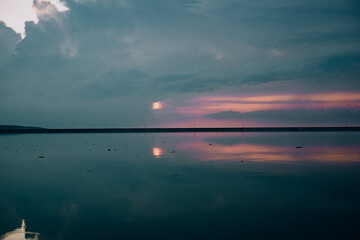 The sunset paints the sky over a still lake, creating a perfect, mirrored reflection. A tranquil...