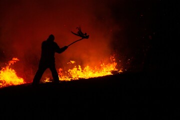 Man fights wildfire at night using improvised tools