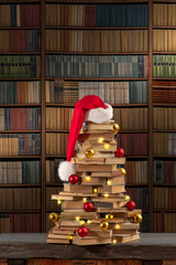 Christmas Tree from old books and Santa Claus hat, lights, balls. New Year in the library with...