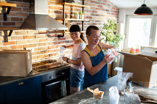 Young lesbian couple unpacking boxes in their new home apartment