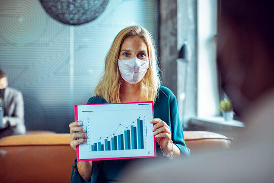 Businesswoman wearing face mask presenting data during office meeting