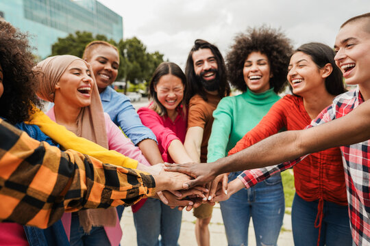Young multiracial people having fun stacking hands outdoor - Diversity and joyful lifestyle concept - Soft focus on african hand
