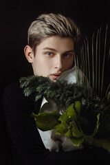 Stylish Young Man Holding Greenery Bouquet Against Dramatic Dark Background 