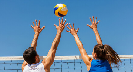 Powerful shot of male and female volleyball players blocking a ball over the net against a clear blue sky, perfect for sports, partnership, and outdoor activity themes