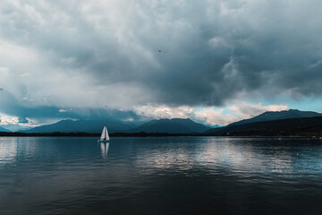 Tranquil Sailing with Mountain Backdrop and Dramatic Clouds