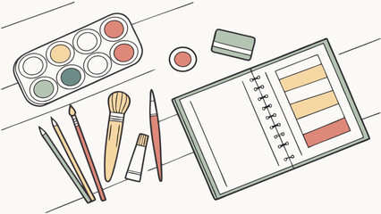 Overhead view of art supplies including paint palette brushes and a notebook on a white surface