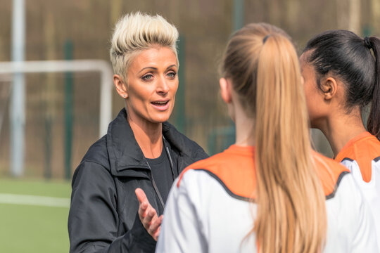 Female coach giving instructions to soccer players on field
