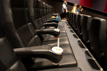 Empty cups and fast food trash left in a movie theater after a film screening, highlighting...