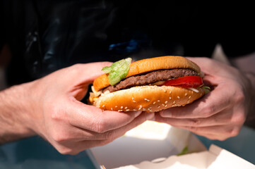 Close-up of a juicy beef burger with melted cheese and sauce, symbol of craving and indulgence in...