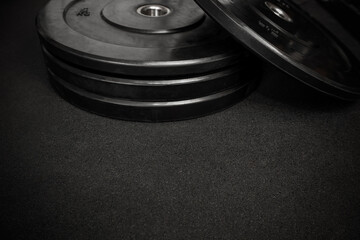 Weight plates on a black gym floor create a powerful image of strength training and fitness preparation