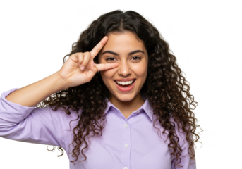 A joyful young woman with curly hair, wearing a purple shirt, smiles and makes a peace sign with her fingers over her eye, isolated on a transparent background