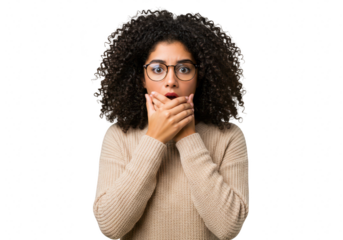 A young woman with curly hair and glasses looks shocked, covering her mouth with her hands isolated on transparent background