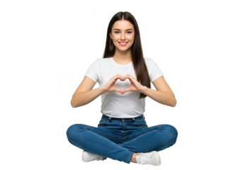 A smiling young woman in jeans and a white tshirt sits crosslegged, forming a heart shape with her hands in front of her chest isolated on transparent background