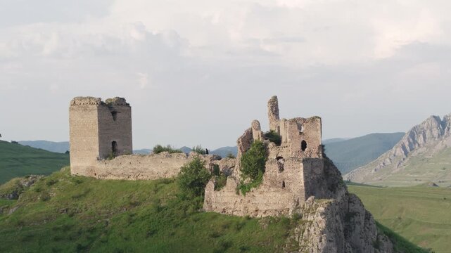 Cinematic drone shot slowly ascending to reveal the medieval Trascău Fortress ruins in Colțești, Romania. An epic historical landmark in the mountains of Transylvania.