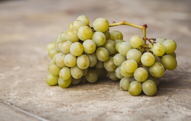 A bunch of green grapes placed on a textured surface