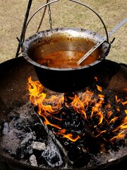 Home-cooked food over the bright red flames in a rural soup in an iron cauldron high in calorie food useful and healthy meat keto diet