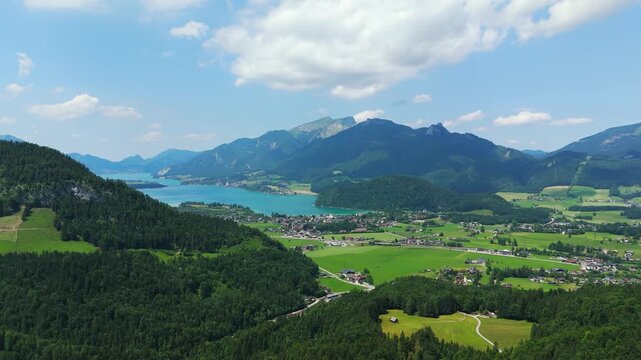 Austrian Lake and small city in idyllic landscape. Aerial wide shot. Sunny day with mountains in summer. Strobl City, Wolfgangsee.