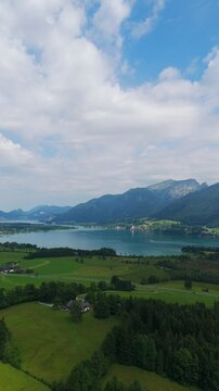 Vertical, aerial: Lake Wolfgang in the Salzburg Alps region on a sunny summer day in Austria, pull out drone shot