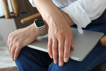 Business woman with electronic watch holding laptop in her hands.