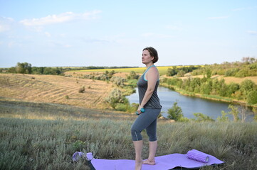 woman exercising outdoors with dumbbells and roller